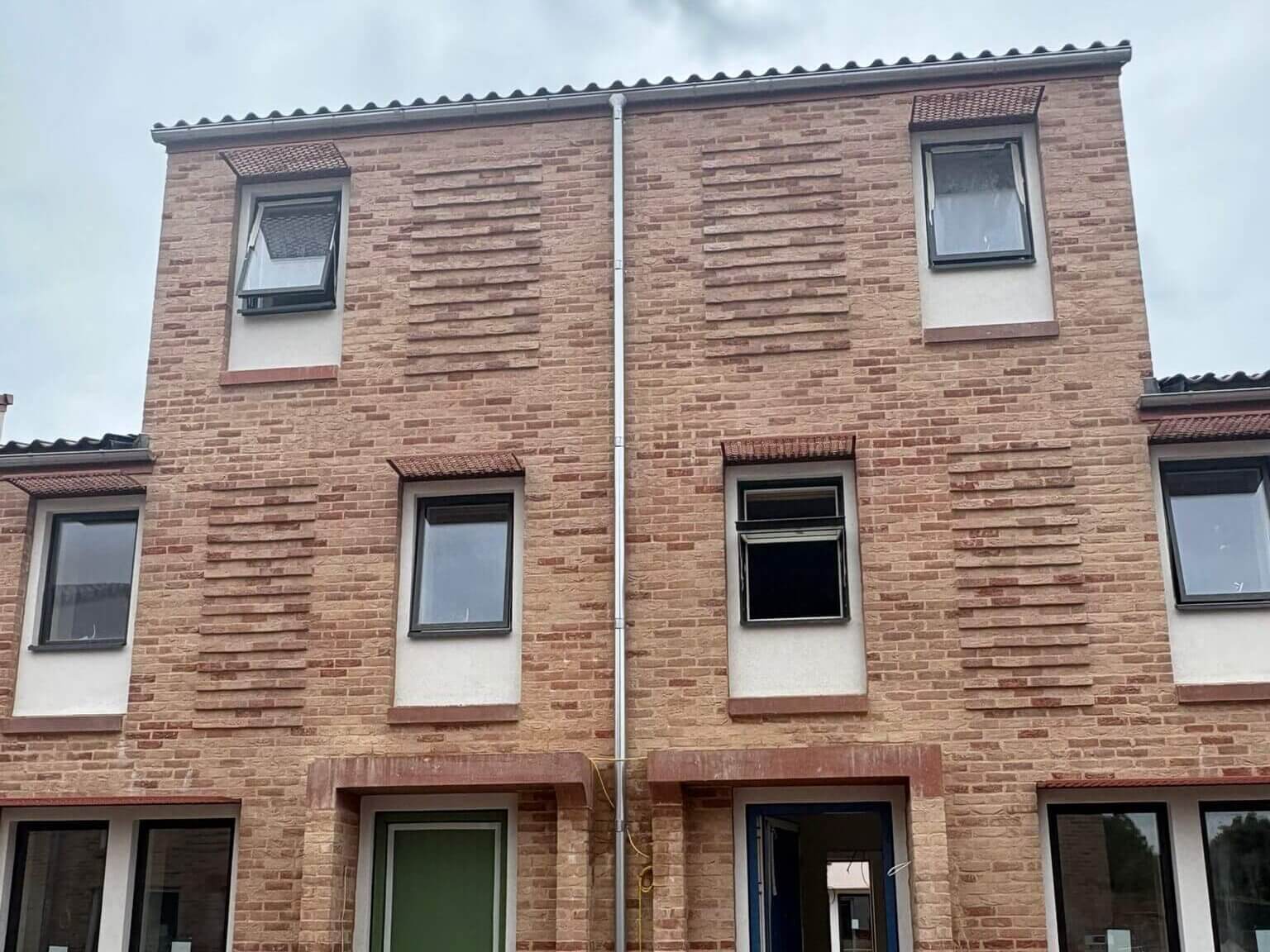 Upward view of new build house facade showing freshly installed galvanised steel guttering and downpipes