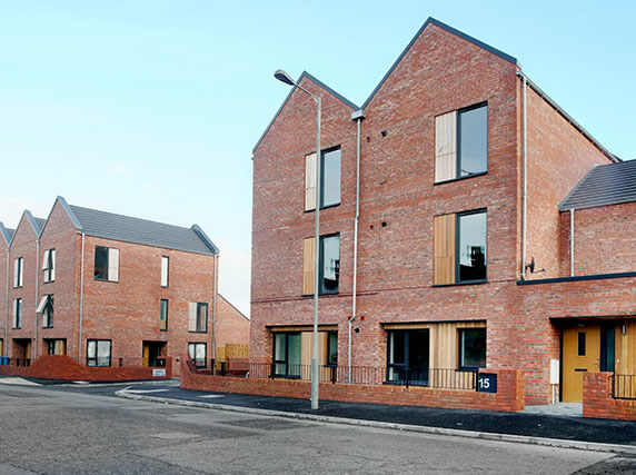 Rainmen Liverpool project - galvanised steel hopper heads positioned at nadir angle of aluminium pike cappings on 3-storey social housing blocks, showing complete rainwater system integration