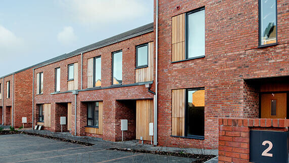 Rainmen Liverpool installation - detailed facade view showing Zambelli galvanised steel guttering, downpipes and aluminium pike cappings on social housing unit