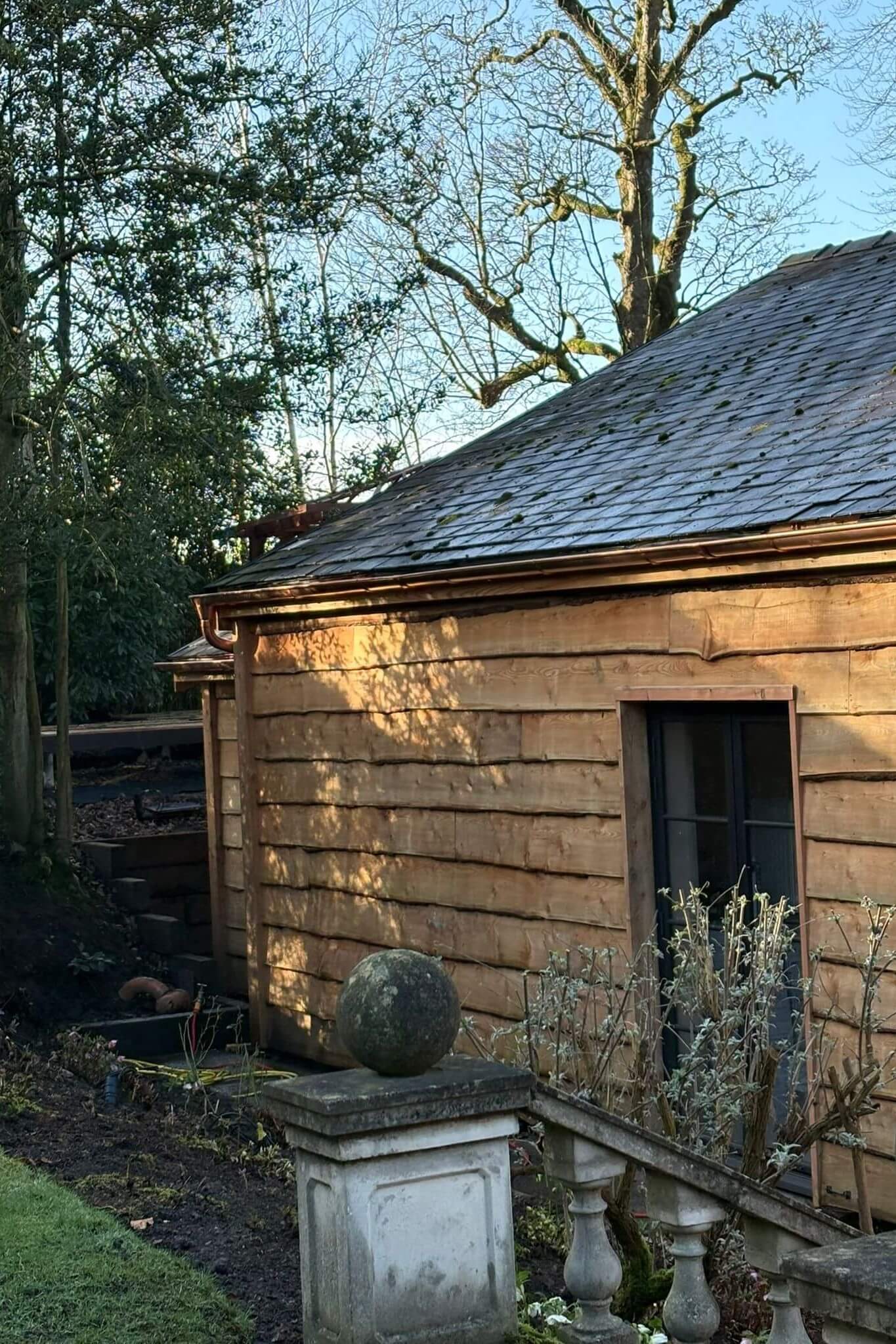 Copper rainwater systems installed at a Grade II listed country house in Lancashire — gutter and downpipe at the corner of the timber-clad pool house
